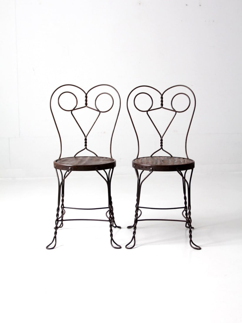 Vintage Pair of Antique Ice Cream Bistro Chairs Black Metal: Vintage Pair of Antique Ice Cream Bistro Chairs Black Metal This pair of early 20th century antique ice cream parlor bistro chairs features a distinctive "spectacle" back design crafted from black met
