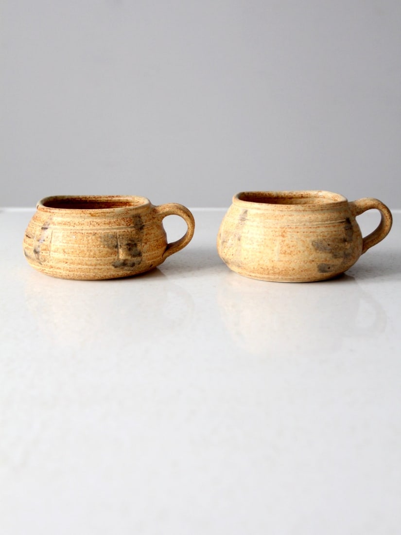 Charming Vintage Studio Pottery Mugs Signed Pair: Charming Vintage Studio Pottery Mugs Signed Pair This charming pair of vintage studio pottery mugs features a rustic hand-crafted design with squat squared shapes and large looped handles. The bases a
