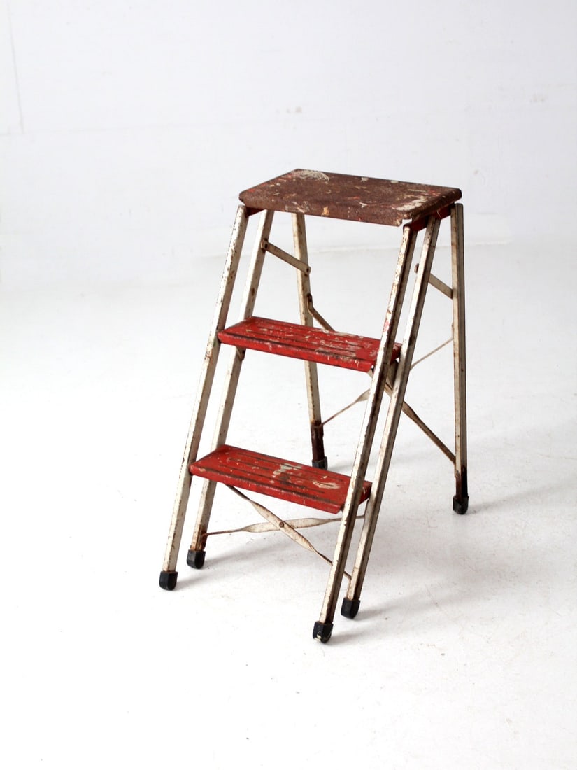 Mid-Century Vintage Folding Step Ladder White Red Decorative Accent: Mid-Century Vintage Folding Step Ladder White Red Decorative Accent This mid-20th century vintage metal folding step ladder is a charming decorative accent that blends functionality with style. Featur