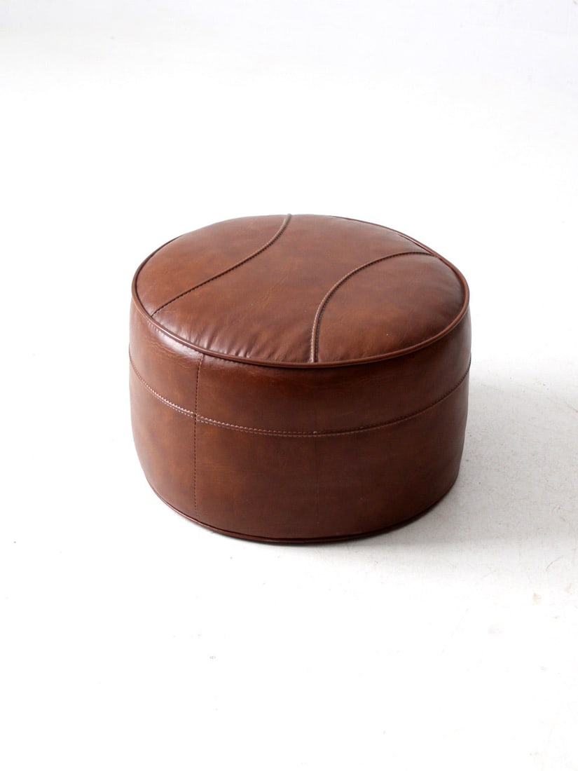 Mid Century Round Cognac Faux Leather Ottoman Pouf: Mid Century Round Cognac Faux Leather Ottoman Pouf Enhance your living space with this stylish Mid Century Faux Leather Ottoman Pouf. It features a rich cognac brown faux leather finish complemented b