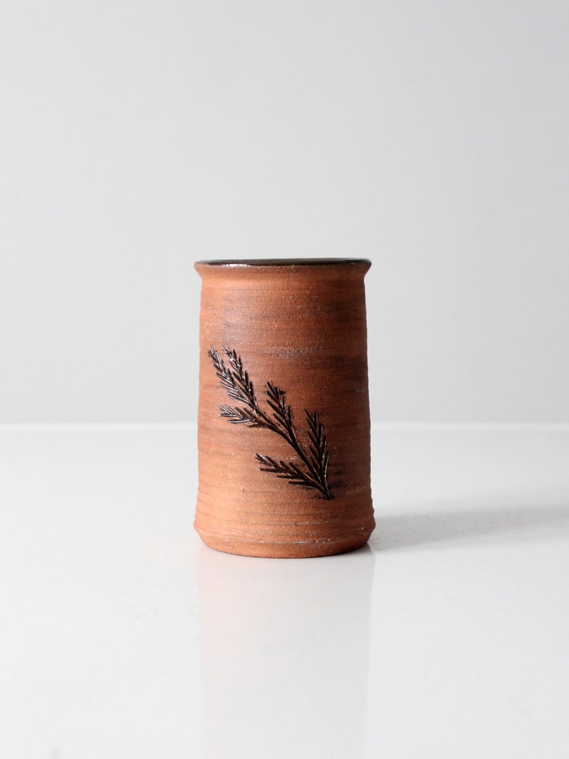Handcrafted Vintage Studio Pottery Vase with Pine Tree Design: Handcrafted Vintage Studio Pottery Vase with Pine Tree Design This vintage studio pottery vase showcases a unique hand-crafted design, featuring a rich brown glazed interior complemented by a natural,