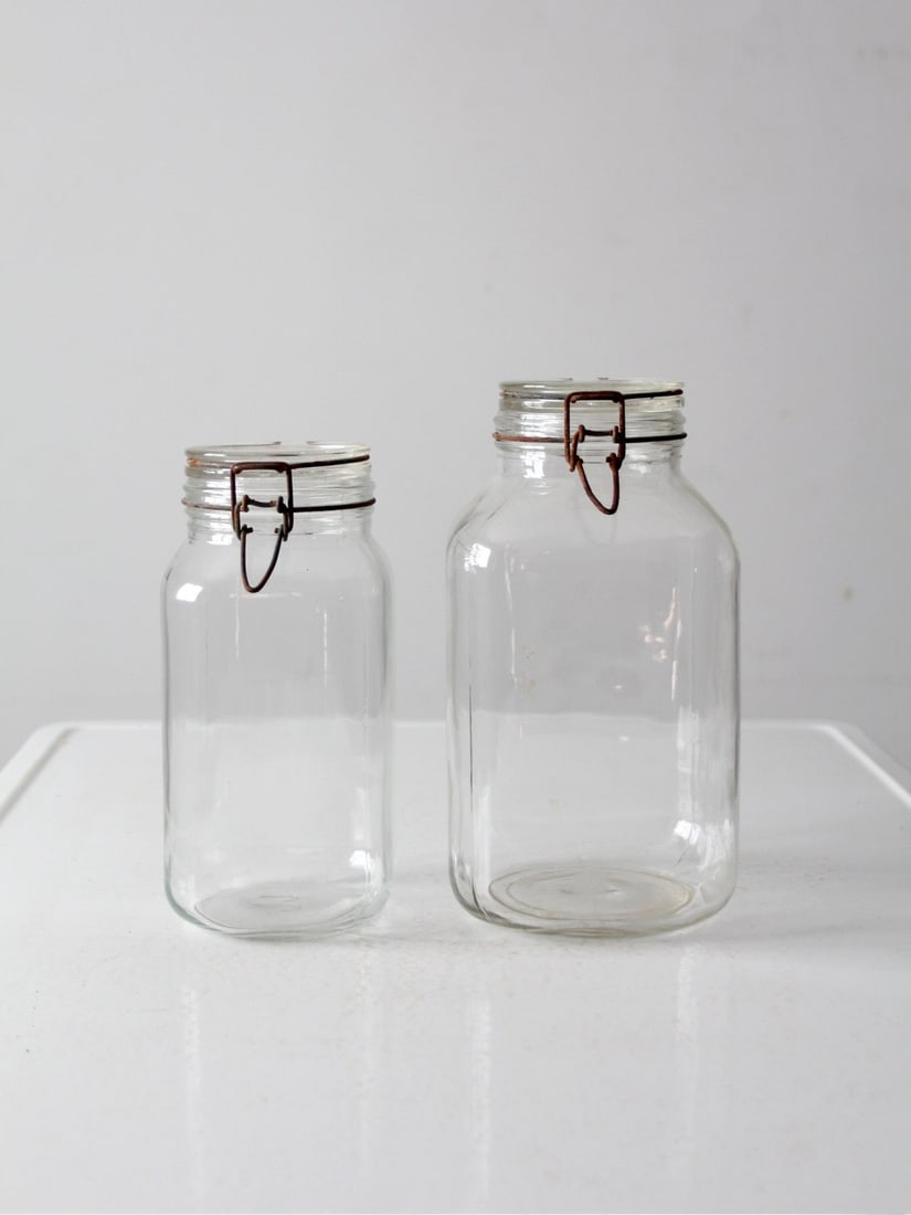 Vintage Italian Ermetico FV Control Glass Jars Set of 2: Vintage Italian Ermetico FV Control Glass Jars Set of 2 This vintage pair of Ermetico FV Control glass jars showcases the elegance of Italian craftsmanship. The set includes one large jar and one smal