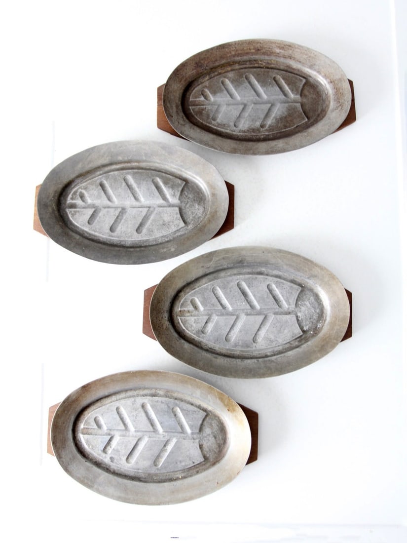 Vintage Aluminum Sizzler Plates Set of 4 with Leaf Motif: Vintage Aluminum Sizzler Plates Set of 4 with Leaf Motif This vintage set of four aluminum sizzler plates features a delightful leaf motif and includes protective wooden chargers. Crafted in Japan for