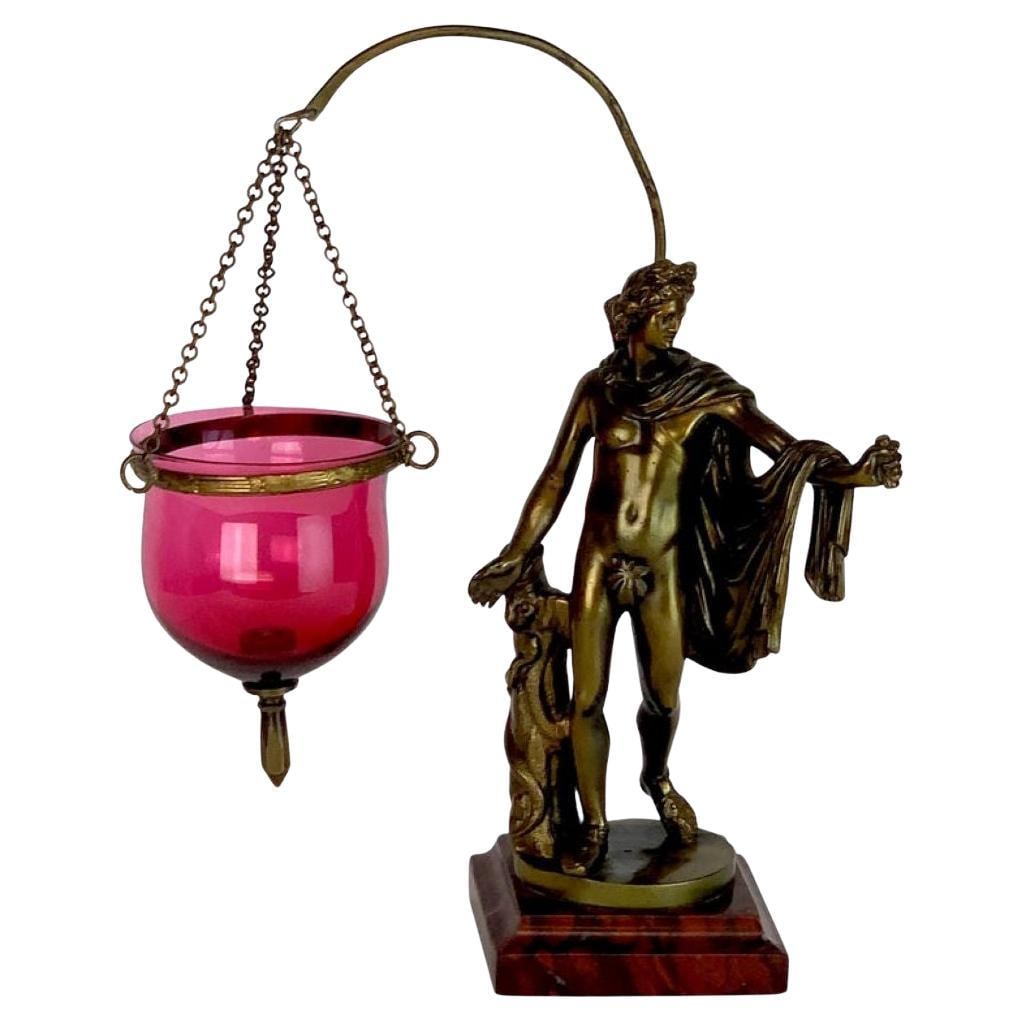 19th C Grand Tour Bronze Apollo Belvedere Lamp with Cranberry Glass Vessel: 19th C Grand Tour Bronze Apollo Belvedere Lamp with Cranberry Glass Vessel Discover this exquisite 19th Century Grand Tour Bronze Apollo Belvedere, a remarkable votive or oil lamp inspired by the clas