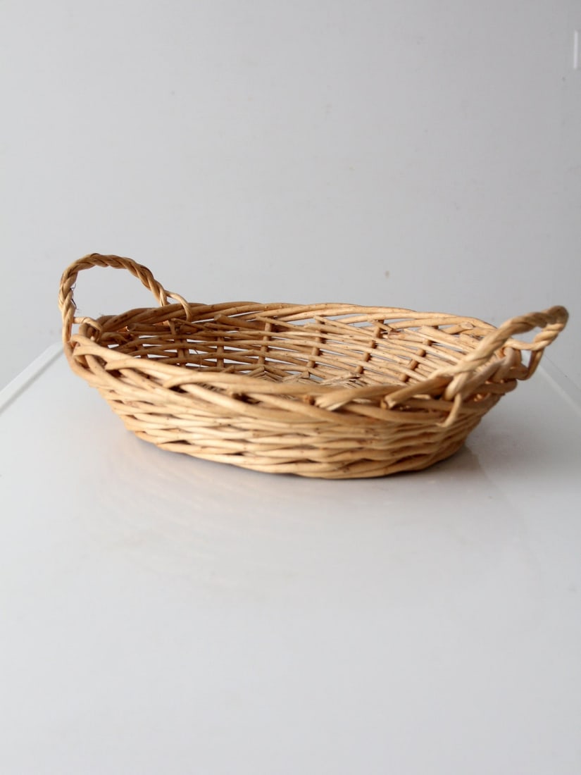 Classic Vintage Oval Woven Wicker Basket with Handles: Classic Vintage Oval Woven Wicker Basket with Handles This vintage woven basket showcases a classic oval shape, complemented by twisted handles and an open-weave design. The light natural tone and han