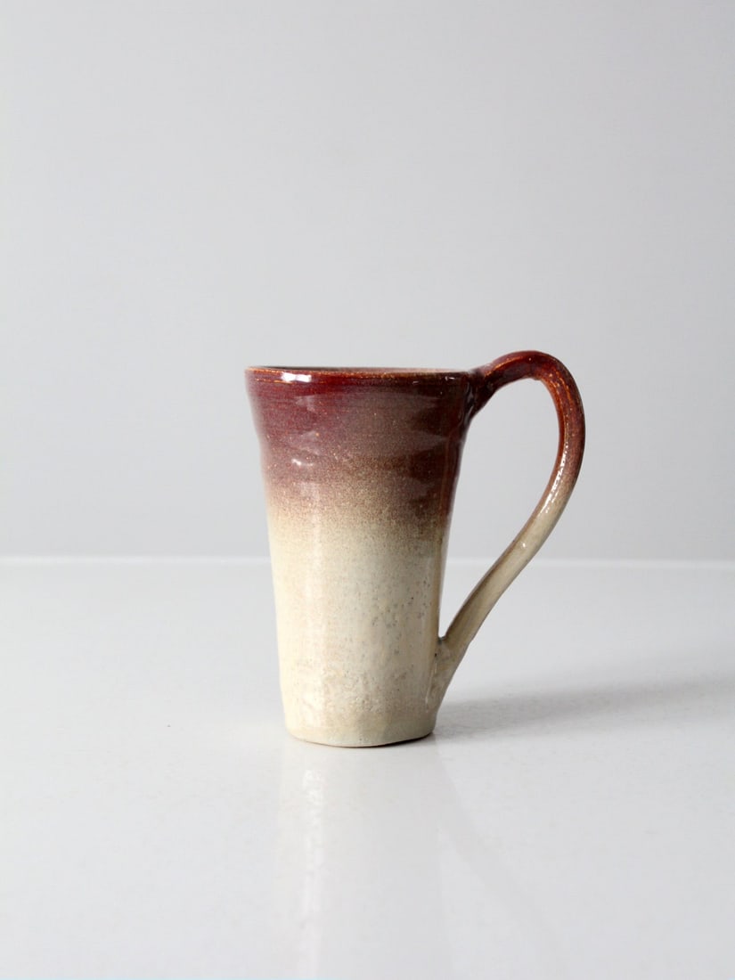 Handcrafted Vintage Studio Pottery Mug with Burgundy Ombre Glaze: Handcrafted Vintage Studio Pottery Mug with Burgundy Ombre Glaze This vintage studio pottery mug showcases exquisite craftsmanship with a weighty hand-crafted ceramic design. It features a creamy whit