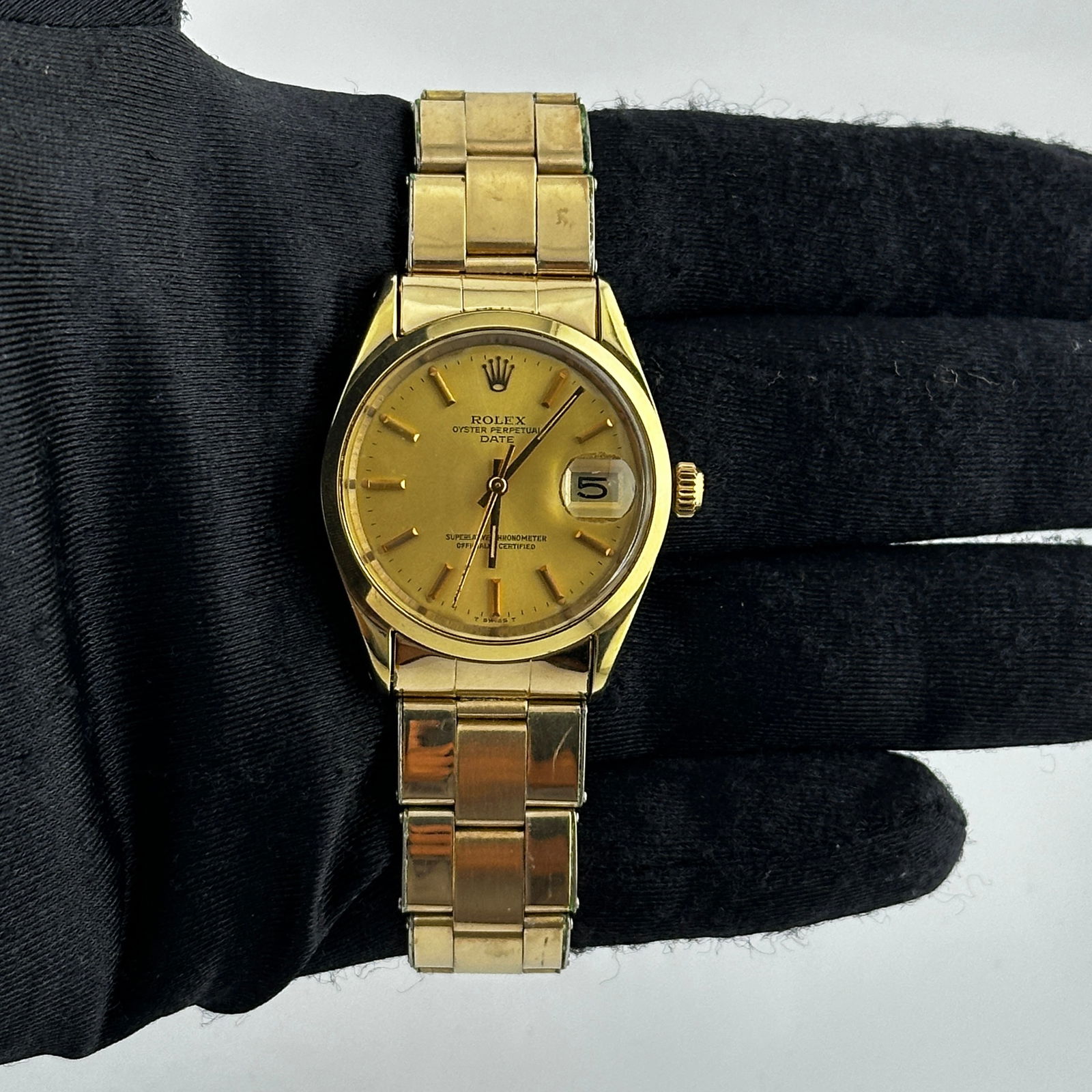 Oyster Perpetual Date Gold Dial Watch Ref 1550 With Papers 1977: Oyster Perpetual Date Gold Dial Watch Ref 1550 With Papers 1977 This is a Rolex Oyster Perpetual Date wristwatch, featuring a gold dial and a smooth bezel. The watch is equipped with an Oyster plated