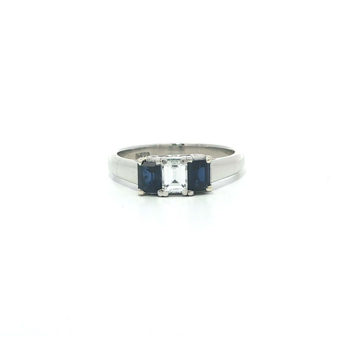 Platinum Three Stone Ring with Rectangular Diamond and Blue Sapphires: Platinum Three Stone Ring with Rectangular Diamond and Blue Sapphires This vintage platinum cocktail ring features a striking three-stone design with a rectangular step-cut natural diamond and two eme
