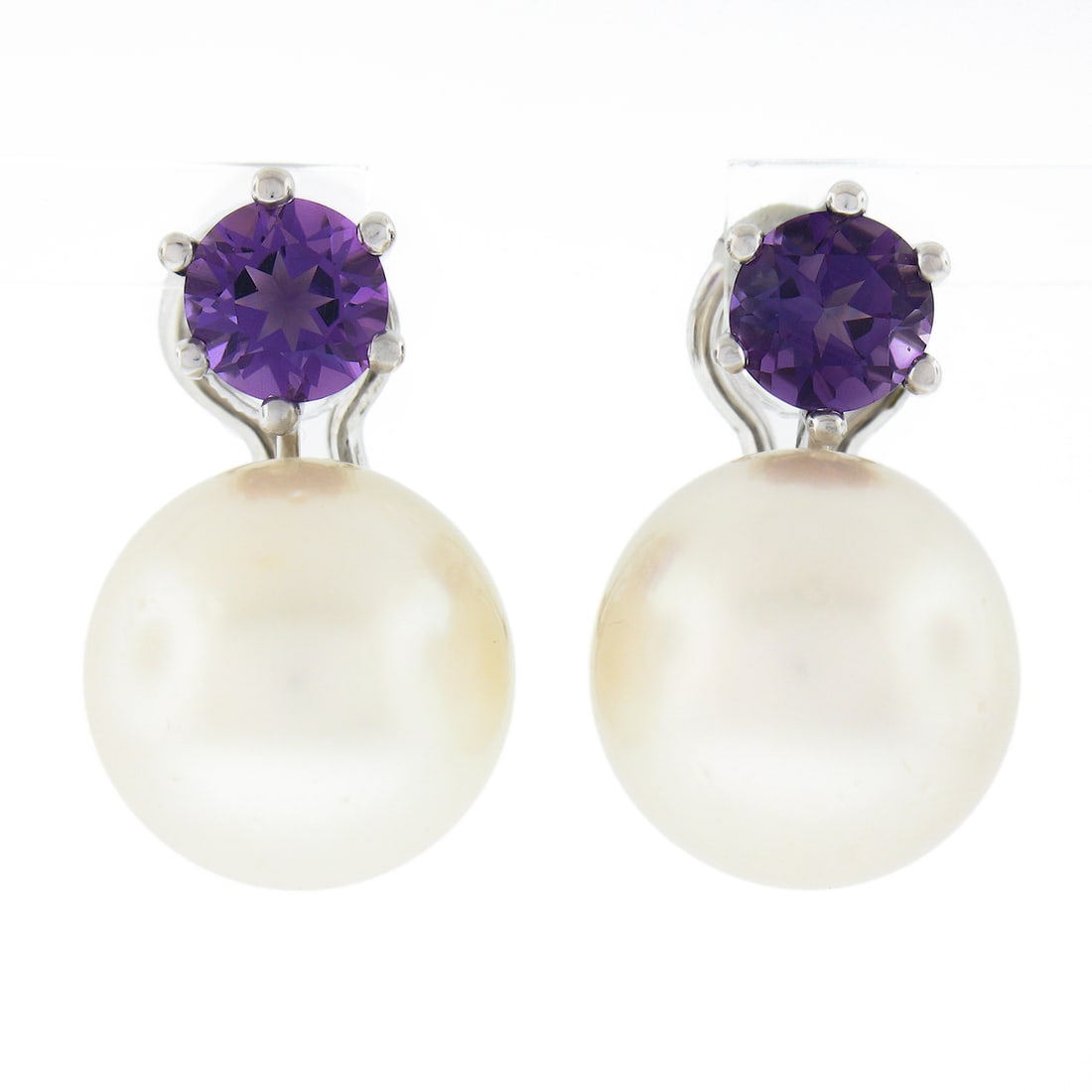 Vintage 18k White Gold Pearl Amethyst Drop Omega Earrings 14mm: Vintage 18k White Gold Pearl Amethyst Drop Omega Earrings 14mm Indulge in the elegance of these vintage drop earrings, crafted from solid 18k white gold. Featuring two stunning 14mm cultured pearls, e