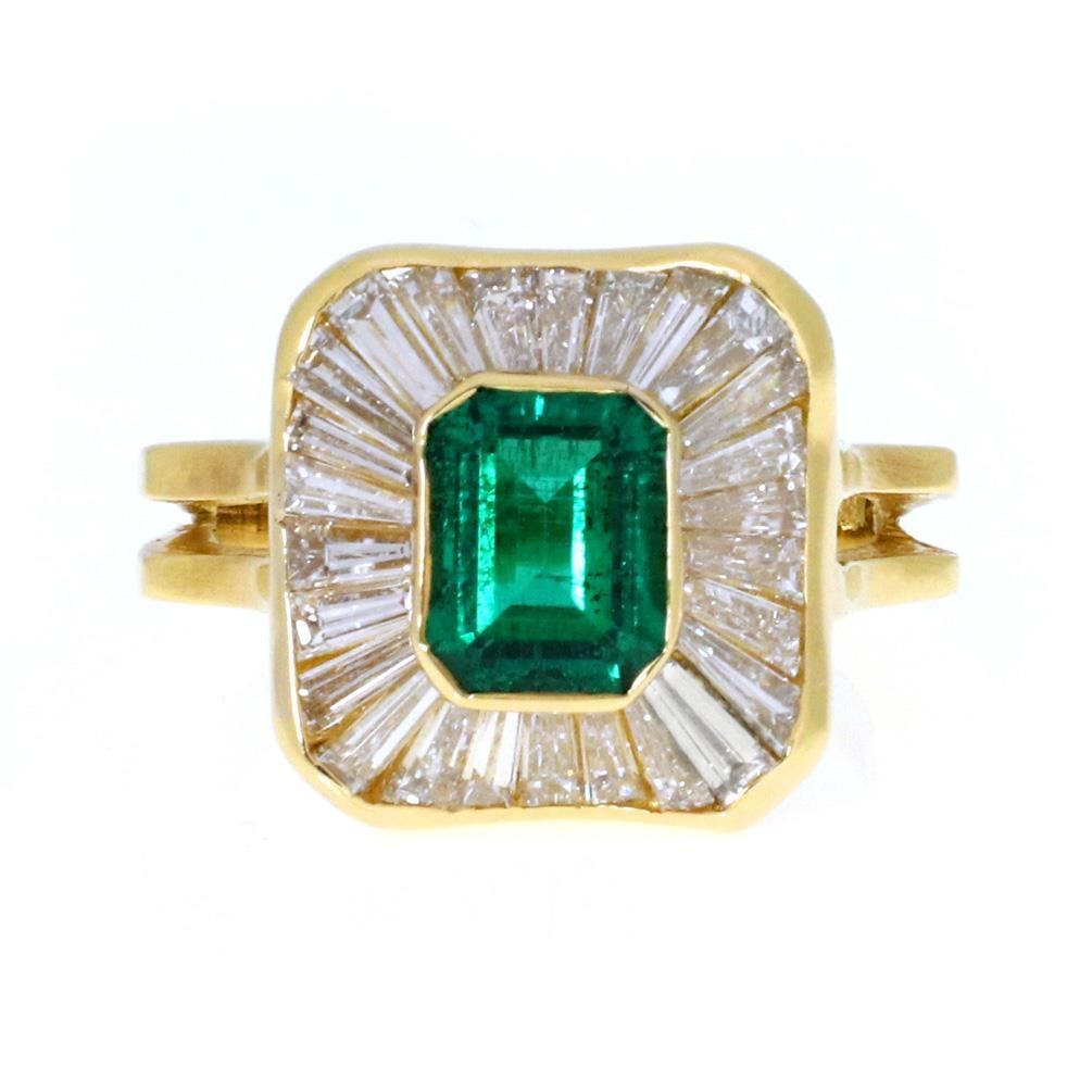 Elegant 18k Yellow Gold Emerald & Baguette Diamond Cocktail Ring: Elegant 18k Yellow Gold Emerald & Baguette Diamond Cocktail Ring This stunning cocktail ring showcases a vibrant emerald gemstone in a secure bezel setting, elegantly surrounded by baguette diamonds.