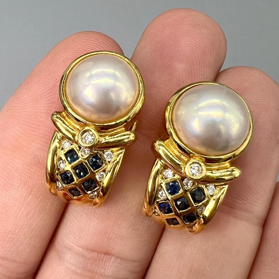 Pearl Sapphire Diamond Earrings in 18K Yellow Gold with 12 Sapphires and 14 Diamonds: Pearl Sapphire Diamond Earrings in 18K Yellow Gold with 12 Sapphires and 14 Diamonds These pre-owned earrings are crafted from 18K yellow gold and feature pearls accented by sapphires and diamonds. Ea