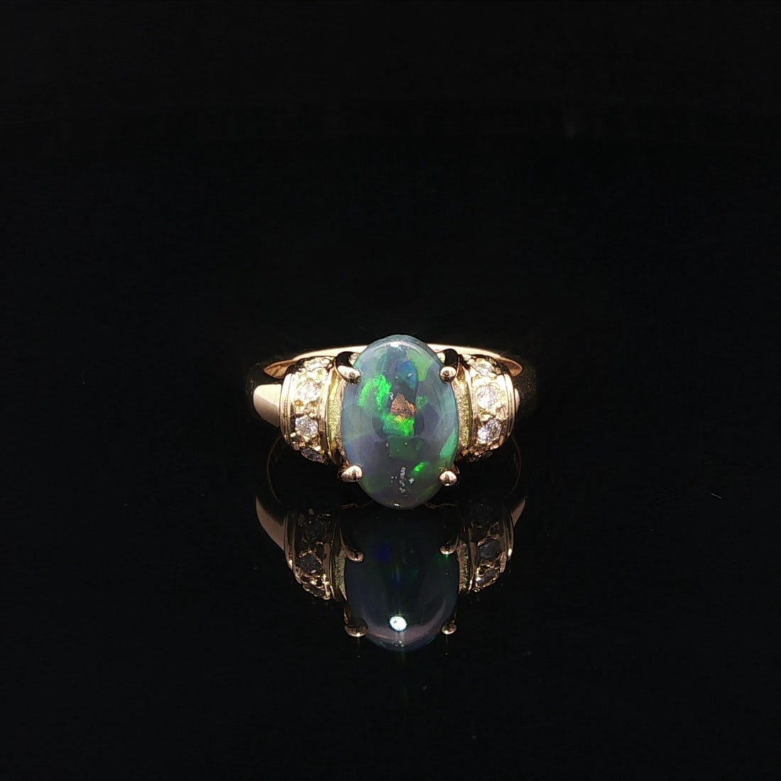 Cocktail Ring in 18k Yellow Gold with Natural Opal and Diamond Accents: Cocktail Ring in 18k Yellow Gold with Natural Opal and Diamond Accents This cocktail ring features a natural gray opal cabochon with a vibrant play of colors, set in solid 18k yellow gold. Accentuatin