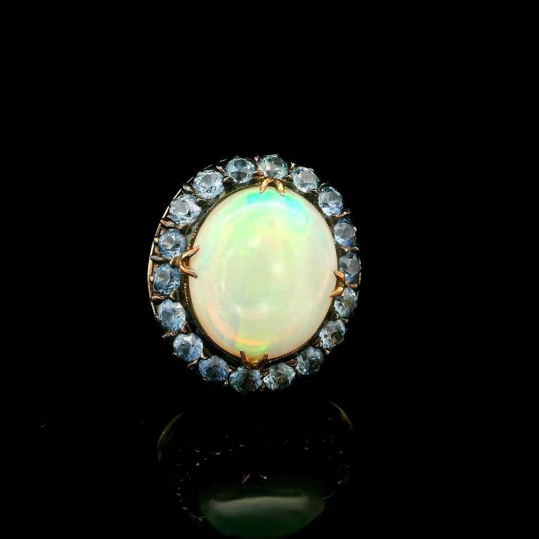 Antique Yellow Gold Opal Cocktail Ring with Cornflower Sapphire Halo: Antique Yellow Gold Opal Cocktail Ring with Cornflower Sapphire Halo This exquisite antique cocktail ring features a stunning oval cabochon opal at its center, showcasing a beautiful play of colors ag