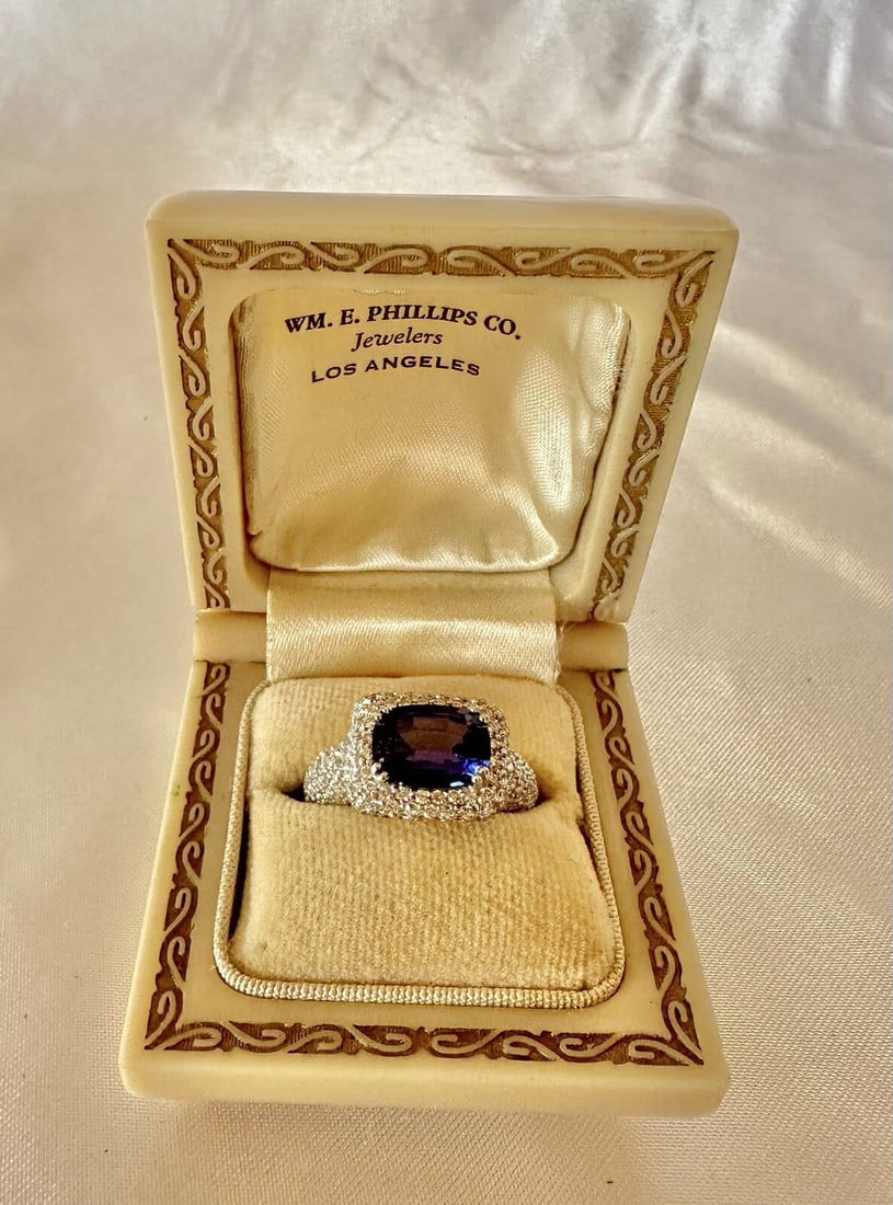 SGJ 18K White Gold Tanzanite Diamond Ring 2.65ct Size 6: SGJ 18K White Gold Tanzanite Diamond Ring 2.65ct Size 6 This stunning 18K white gold ring features a vibrant violet-blue cushion-shaped tanzanite at its center, weighing 2.65 ct. The ring is adorned w