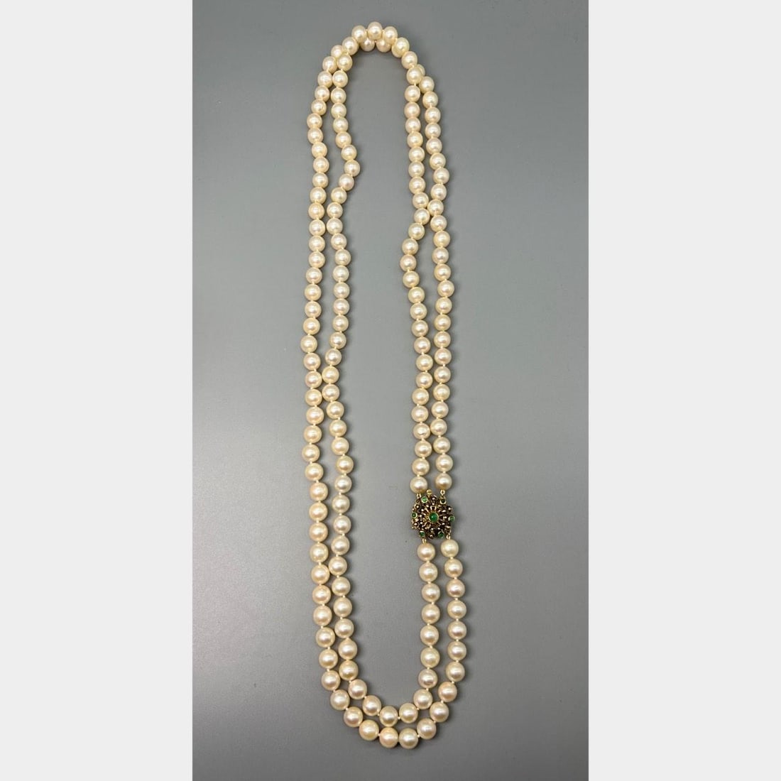 1950s Cultured Pearl and 14K Gold Necklace with Emerald Accents 30 Inch: 1950s Cultured Pearl and 14K Gold Necklace with Emerald Accents 30 Inch This 1950s necklace features cultured pearls measuring between 8.9 mm and 8.75 mm, set in 14K yellow gold. The necklace is furth