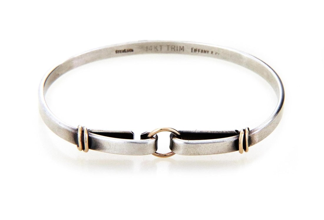 Vintage Bangle in Sterling with 14k Yellow Gold Double Loop by Tiffany & Co.: Vintage Bangle in Sterling with 14k Yellow Gold Double Loop by Tiffany & Co. This vintage bangle by Tiffany & Co. is crafted from sterling silver with 14k yellow gold trim. The design features a doubl