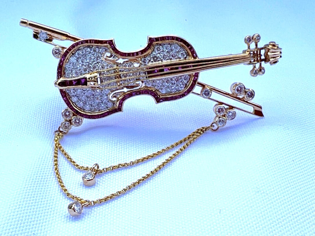 French 18K Gold Ruby Diamond Violin Brooch Classical Music Jewelry: French 18K Gold Ruby Diamond Violin Brooch Classical Music Jewelry This exquisite French brooch features a stunning violin design, crafted from 18K yellow gold. It showcases a remarkable combination o