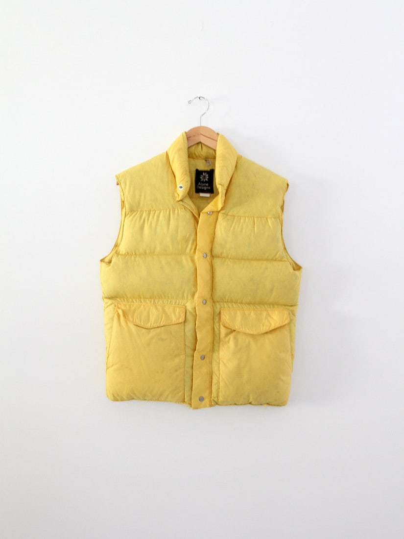 1970s Vintage Yellow Nylon Puff Vest with Pockets: 1970s Vintage Yellow Nylon Puff Vest with Pockets Embrace the retro style with this vibrant 1970s vintage nylon puff vest in a striking yellow hue. This down-filled vest provides warmth and comfort, f