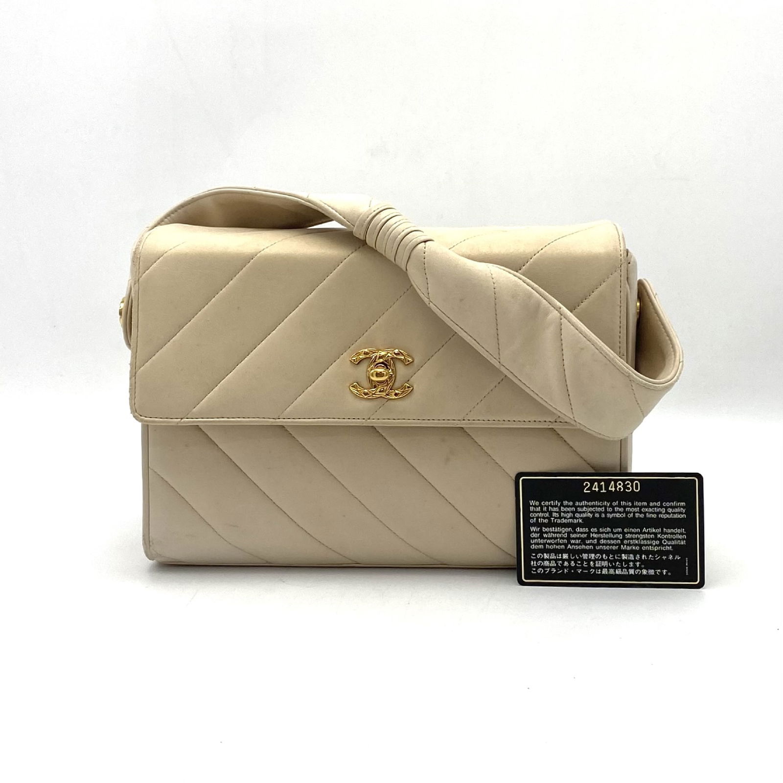 Chanel Olsen beige lambskin handbag with mirror and turn lock: Chanel Olsen beige lambskin handbag with mirror and turn lock This Chanel Olsen handbag features beige leather with a bias stitch design and a signature Coco Mark turn lock closure. The bag includes a