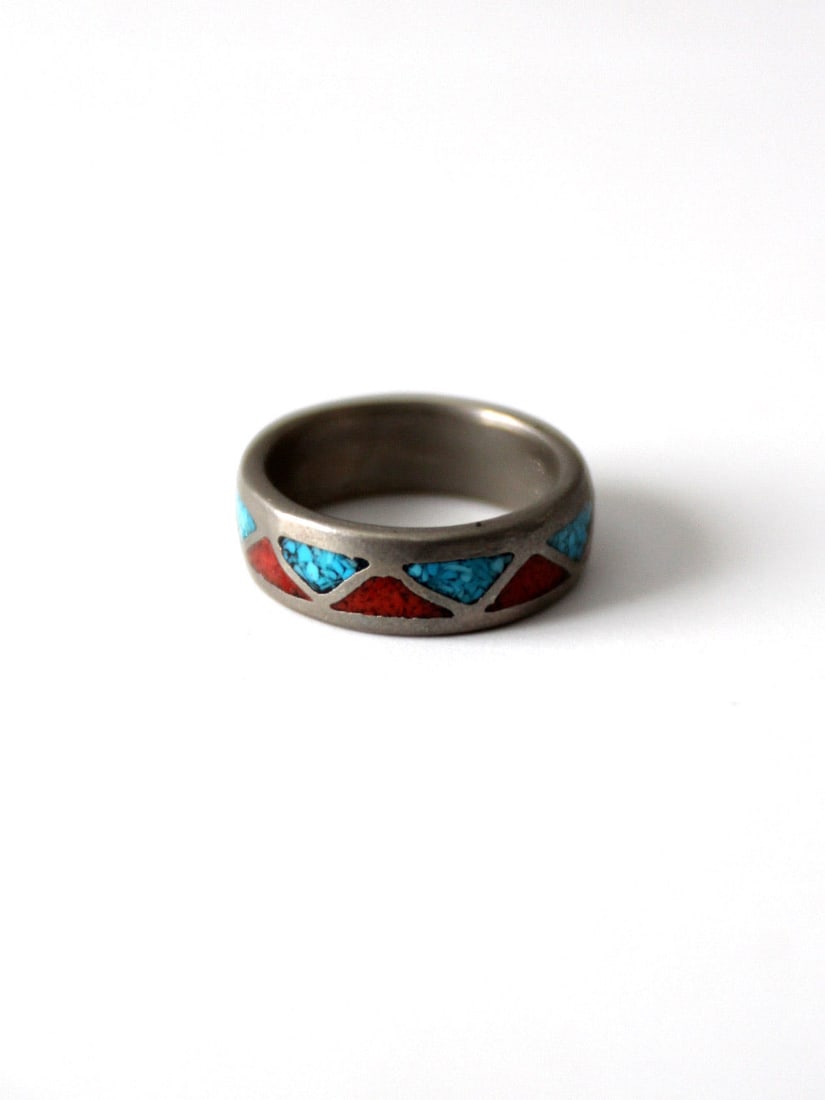 Silver Tone Vintage Ring with Turquoise and Coral Stones: Silver Tone Vintage Ring with Turquoise and Coral Stones This vintage silver-tone ring features a bold statement band design, accented with turquoise and coral stone settings. The colorful inlay and c