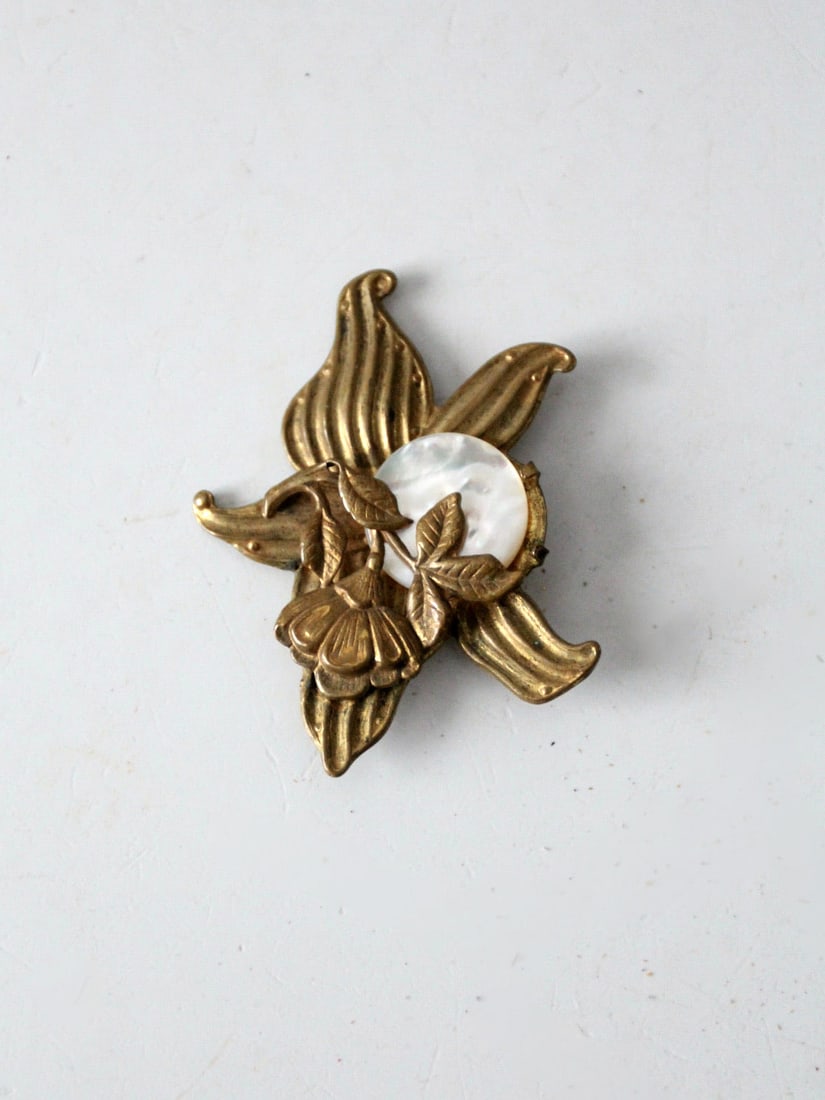 Antique Floral Gold Tone Brooch with Mother of Pearl Cabochon: Antique Floral Gold Tone Brooch with Mother of Pearl Cabochon This exquisite antique brooch showcases a beautiful floral design crafted from gold tone metal, featuring a round prong set mother of pear