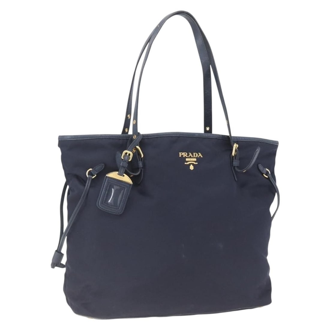 Prada Navy Nylon Tote Bag with Gold Accents and Name Tag: Prada Navy Nylon Tote Bag with Gold Accents and Name Tag This PRADA tote bag features a navy nylon exterior with gold-tone accents and includes a name tag accessory. Made in Italy, the bag shows signi