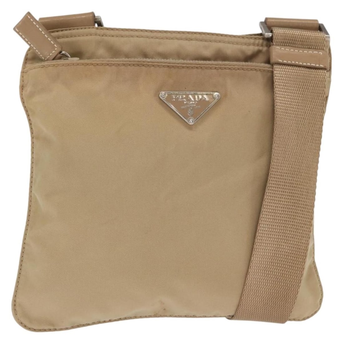 Prada Beige Nylon Shoulder Bag with Silver Accents: Prada Beige Nylon Shoulder Bag with Silver Accents This PRADA shoulder bag is crafted from beige nylon with silver-tone details. Made in Italy, it features an adjustable shoulder strap and a compact d