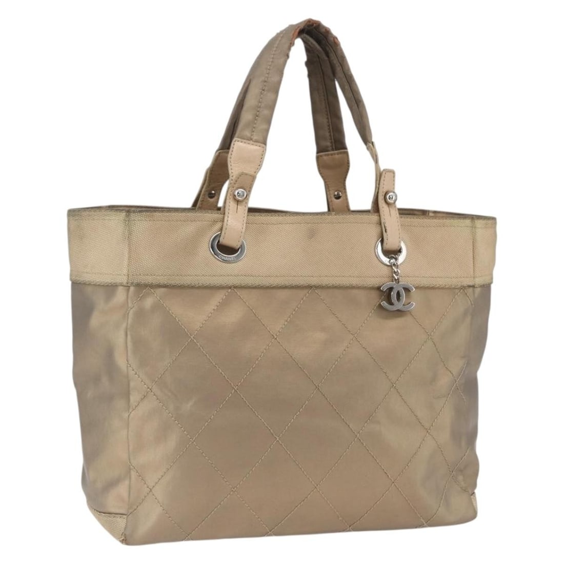 Paris Biarritz MM Gold Coated Canvas Tote by CHANEL with Charm: Paris Biarritz MM Gold Coated Canvas Tote by CHANEL with Charm This CHANEL Paris Biarritz MM tote bag is crafted from gold coated canvas and features a signature CC detail. Designed in a medium size,