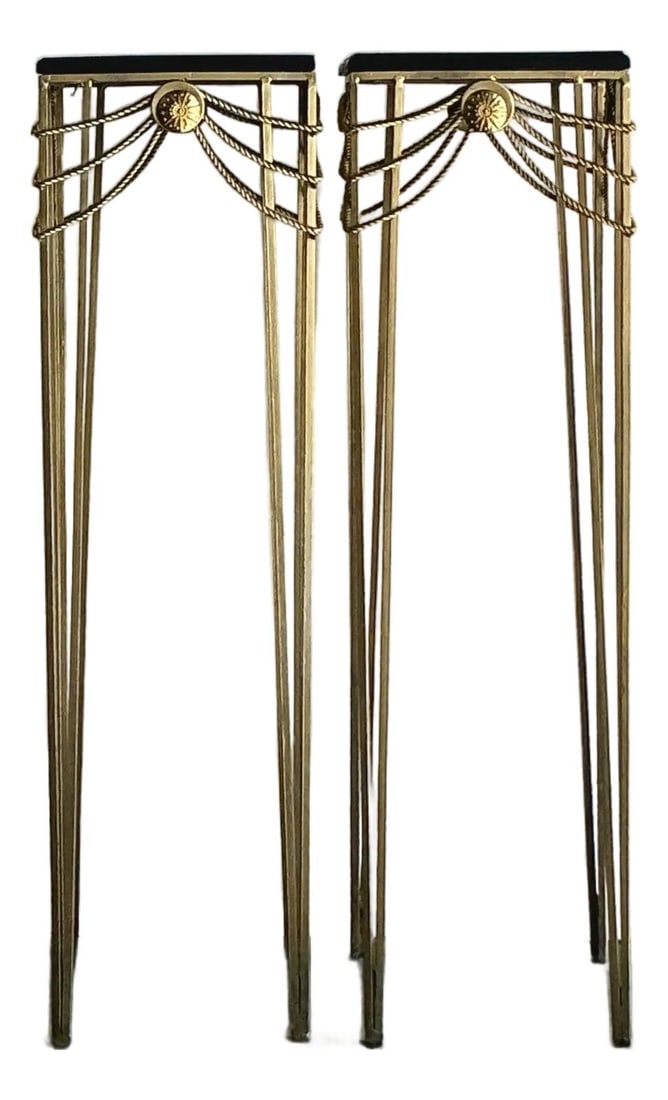 Pair of Gold Finish Neoclassical Pedestal Stands With Swag Rosette Detail: Pair of Gold Finish Neoclassical Pedestal Stands With Swag Rosette Detail This pair of vintage Hollywood Regency pedestals features a slender, open-frame design crafted from iron with a gold finish. E
