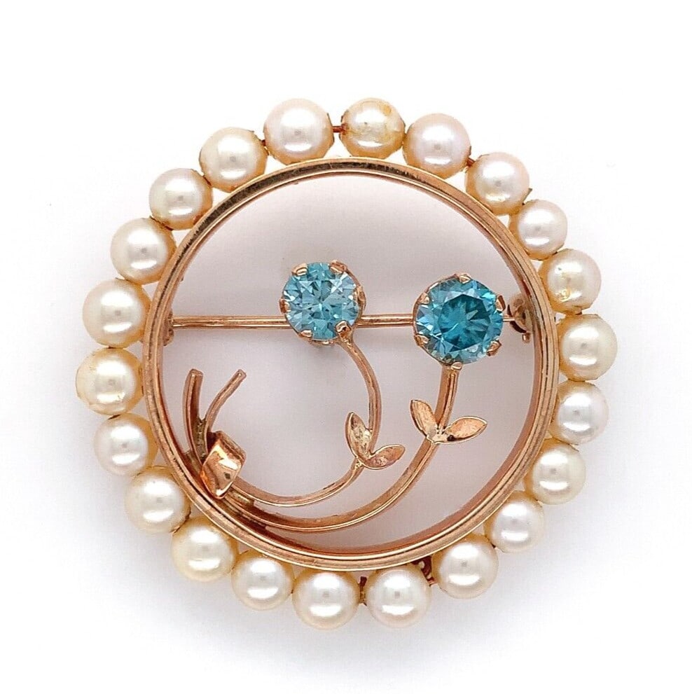 1940s 14k Yellow Gold Pin with Blue Zircon Flowers and Cultured Pearl Circle: 1940s 14k Yellow Gold Pin with Blue Zircon Flowers and Cultured Pearl Circle This retro circle pin from the 1940s is crafted in 14k yellow gold and features a pair of round brilliant teal blue zircons