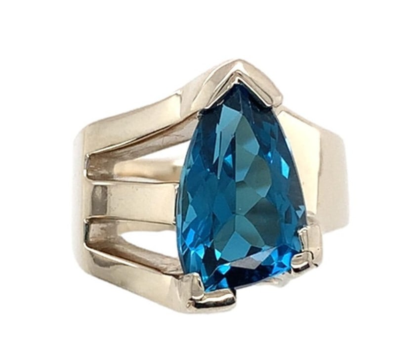 14k White Gold Custom Blue Topaz Ring by Rose Holloway Jewelers: 14k White Gold Custom Blue Topaz Ring by Rose Holloway Jewelers This exquisite 14k white gold ring showcases a stunning triangular cut genuine natural blue topaz, featuring a captivating dark teal hue