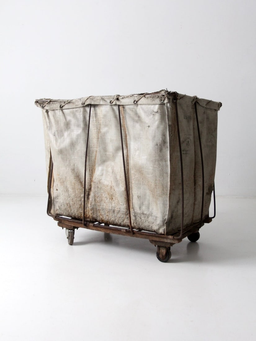 Vintage Industrial Laundry Cart with Shamrock Branding and Caster Wheels: Vintage Industrial Laundry Cart with Shamrock Branding and Caster Wheels This vintage industrial laundry cart showcases the iconic Shamrock branding on its original reinforced canvas bag. The bag is