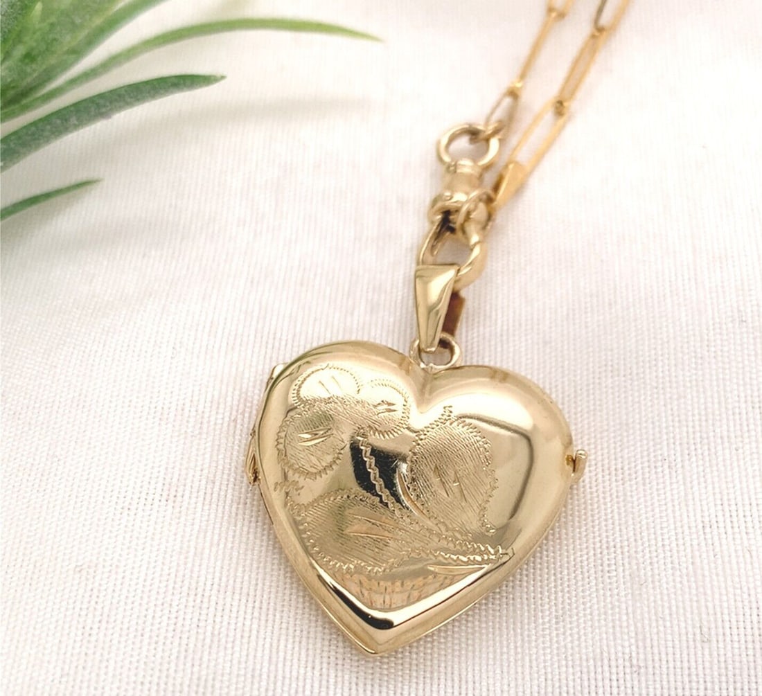 14k Yellow Gold Heart Locket with Engraved Clover on Elongated Chain: 14k Yellow Gold Heart Locket with Engraved Clover on Elongated Chain This exquisite 14k Yellow Gold Heart Locket features a charming engraved clover design, symbolizing good luck. The heart-shaped pen