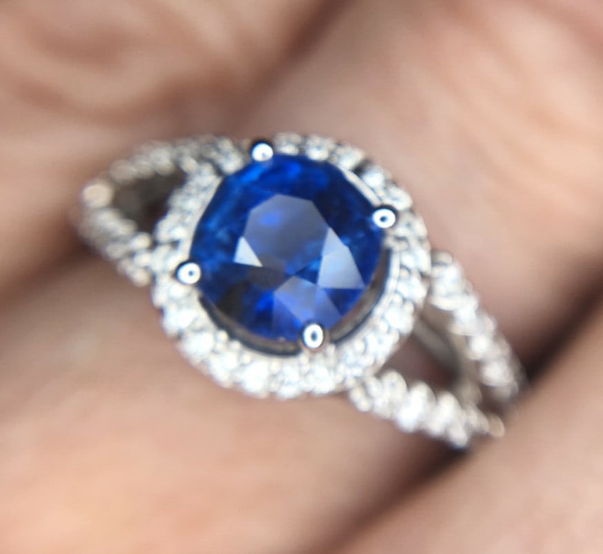 14k White Gold 2 Carat Blue Sapphire Diamond Halo Ring JAGI Certified: 14k White Gold 2 Carat Blue Sapphire Diamond Halo Ring JAGI Certified This stunning 14k white gold halo ring showcases a genuine natural blue sapphire weighing 1.53 carats. The sapphire features a vel