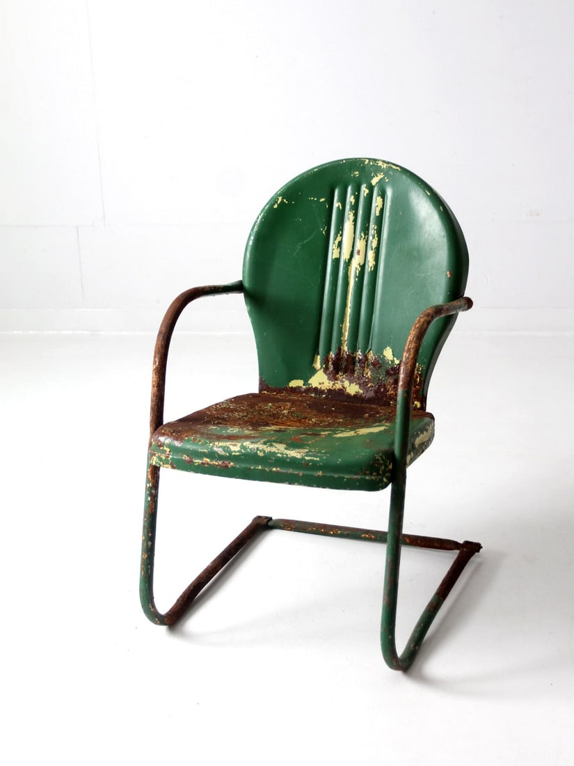 Mid Century Art Deco Patio Chair Distressed Green Yellow: Mid Century Art Deco Patio Chair Distressed Green Yellow This mid-century patio chair features an art deco design with a cantilever bouncer frame and a scalloped back. The classic lawn chair is adorne