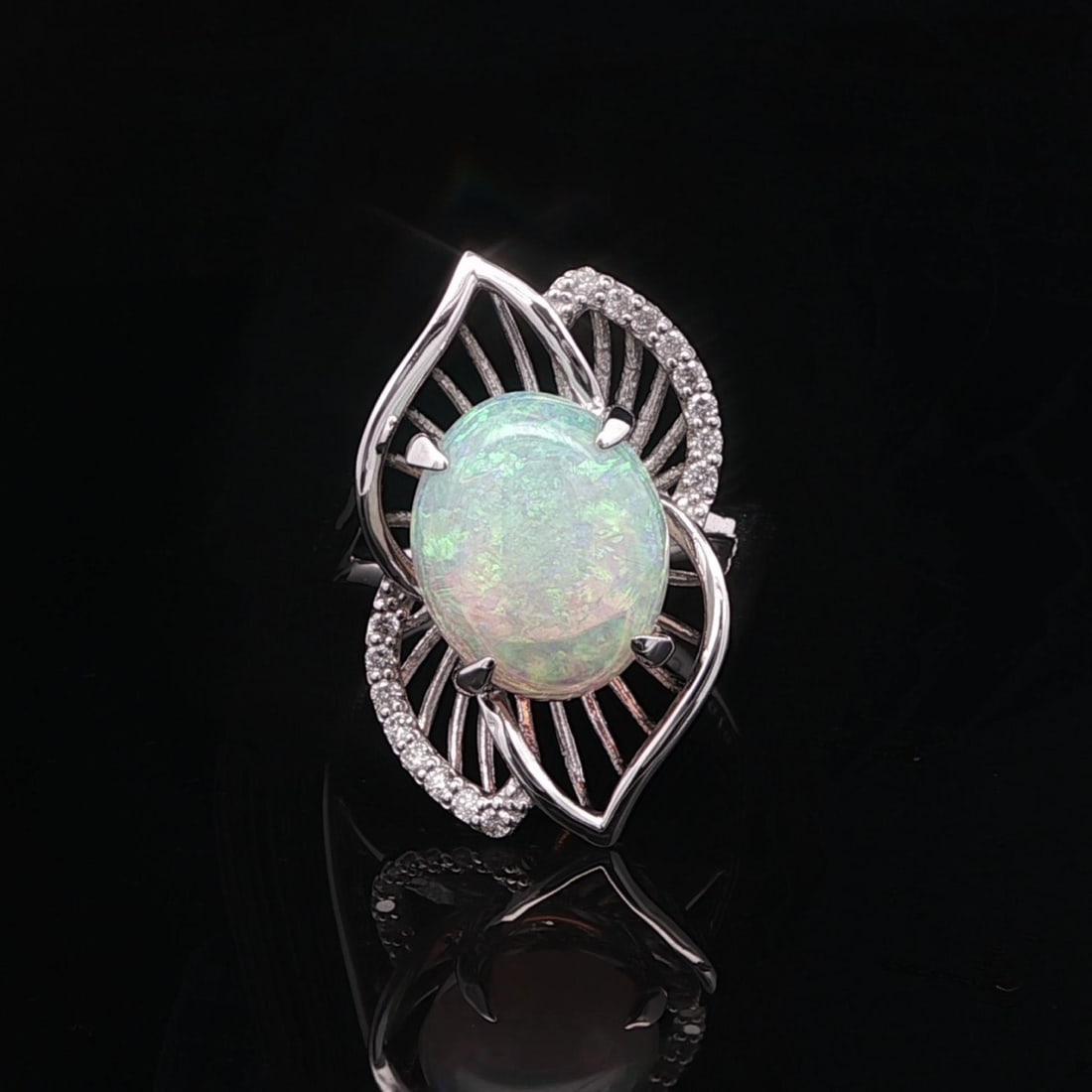 Cocktail Ring in 18k White Gold with Cabochon Opal and Diamond Leaf Motif: Cocktail Ring in 18k White Gold with Cabochon Opal and Diamond Leaf Motif This exquisite cocktail ring features a natural white opal in an oval cabochon cut, accented by sixteen round brilliant cut na