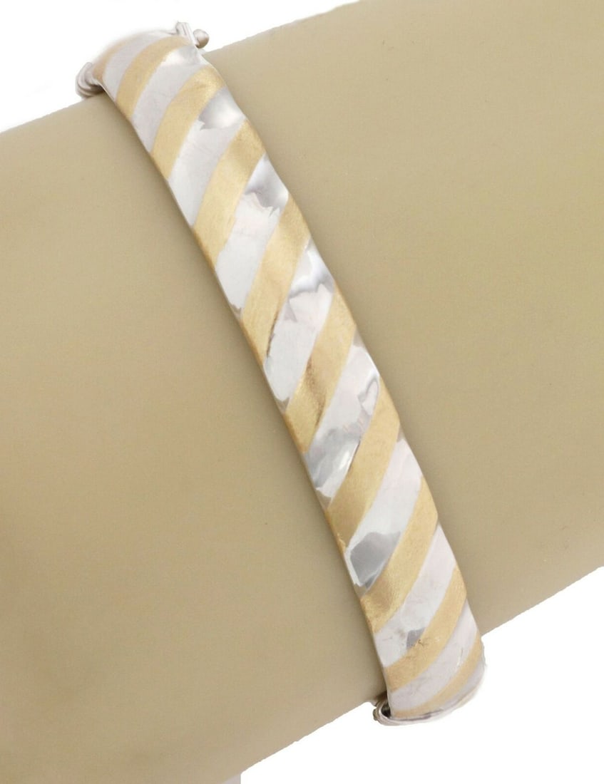 Oval Hinged Bangle Bracelet in 14k Two Tone Gold Made in Italy: Oval Hinged Bangle Bracelet in 14k Two Tone Gold Made in Italy This elegant bangle bracelet is crafted in hollow 14k yellow and white gold, featuring a distinctive slanted stripe pattern that wraps ar