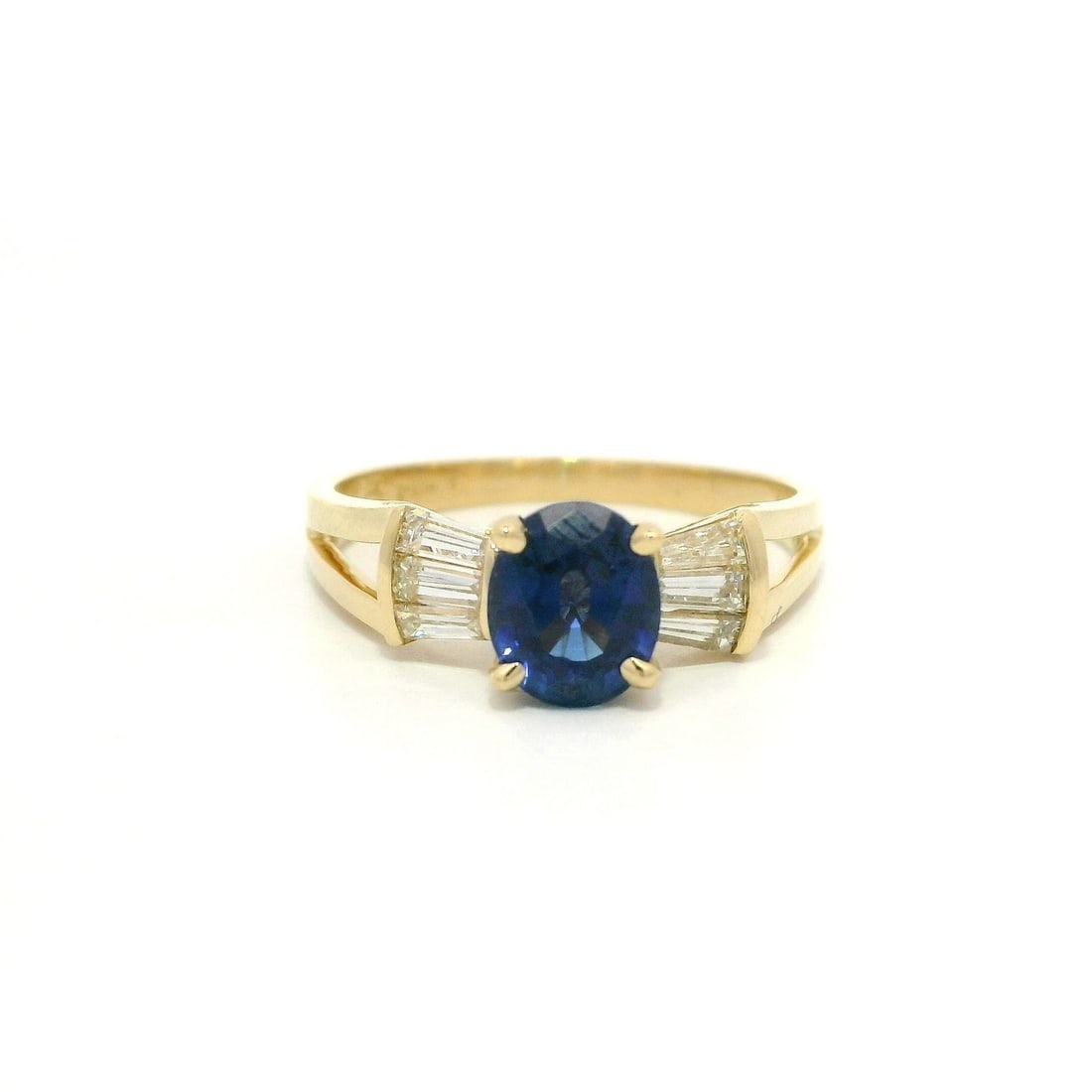 14k Gold Bow Style Ring Royal Blue Sapphire 1.49ctw Baguette Diamonds: 14k Gold Bow Style Ring Royal Blue Sapphire 1.49ctw Baguette Diamonds This exquisite ring features a stunning oval-cut natural sapphire with a vivid royal blue color, measuring approximately