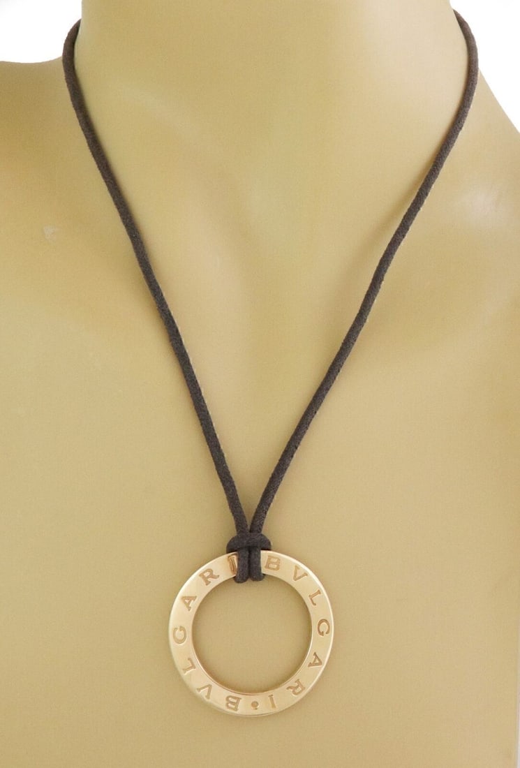 18k Yellow Gold Pendant Necklace by Bvlgari Open Wave Engraved Design on Cord: 18k Yellow Gold Pendant Necklace by Bvlgari Open Wave Engraved Design on Cord This Bvlgari necklace features an 18k yellow gold pendant with an open wave design and engraved detailing. The pendant is