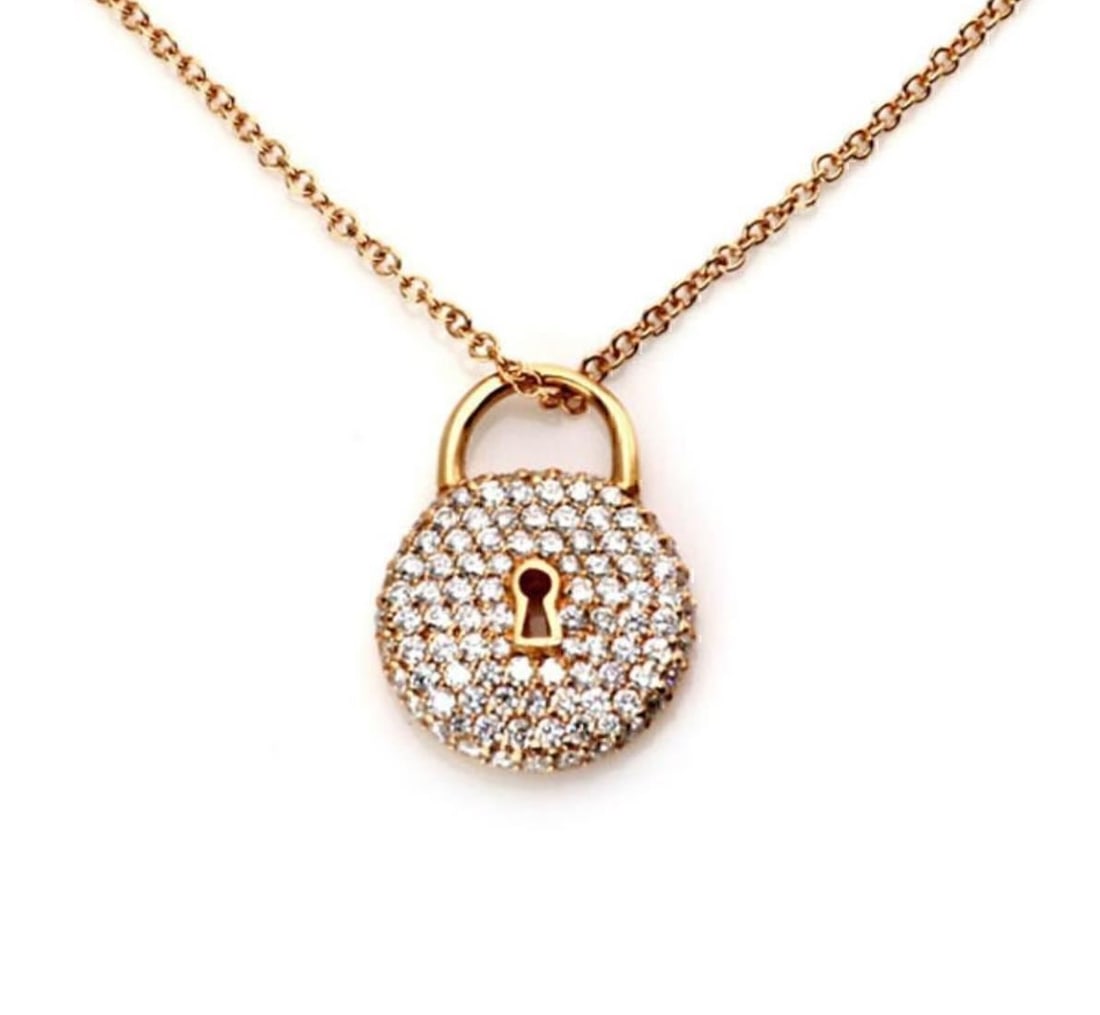 Diamond Padlock Pendant Necklace in 18k Rose Gold by Tiffany & Co.: Diamond Padlock Pendant Necklace in 18k Rose Gold by Tiffany & Co. This Tiffany & Co. pendant necklace features a classic round padlock design crafted in 18k rose gold. The pendant is adorned with a n