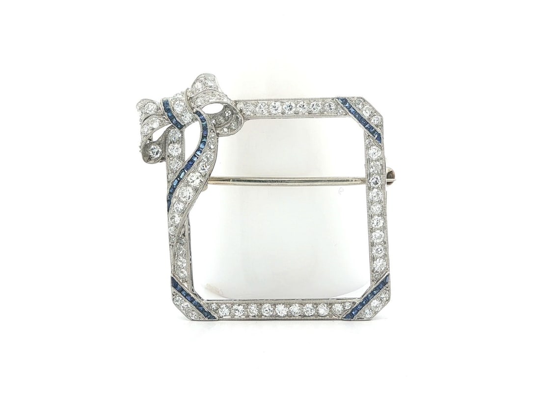 Art Deco Platinum Brooch With Diamonds And Synthetic Blue Sapphires: Art Deco Platinum Brooch With Diamonds And Synthetic Blue Sapphires This Art Deco brooch features an open square design with cut corners and a ribbon top. Crafted from solid 850+ platinum with a 14k w