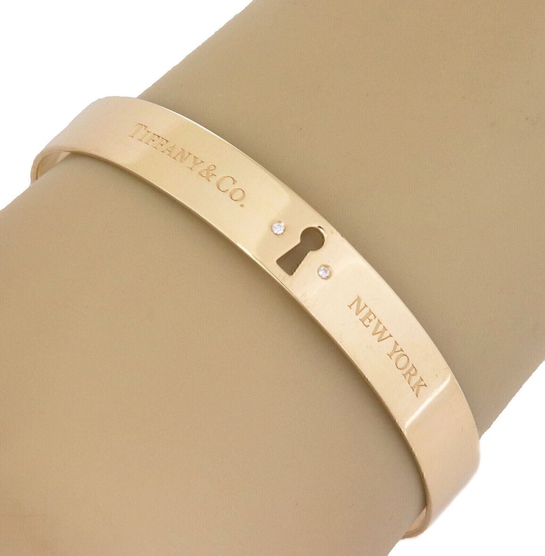 18k Yellow Gold Keyhole Lock Bangle Bracelet by Tiffany & Co.: 18k Yellow Gold Keyhole Lock Bangle Bracelet by Tiffany & Co. This Tiffany & Co. bangle bracelet is crafted from 18k yellow gold and features a keyhole lock design. The bracelet has an inner circumfer