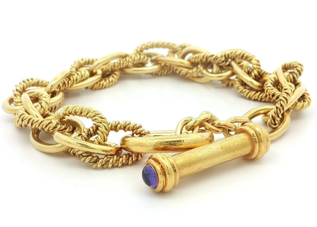 18k Yellow Gold Interlocking Toggle Bracelet with Purple Sapphires: 18k Yellow Gold Interlocking Toggle Bracelet with Purple Sapphires This stunning bracelet features an elegant design crafted from solid 18k yellow gold, showcasing a unique combination of plain and tw