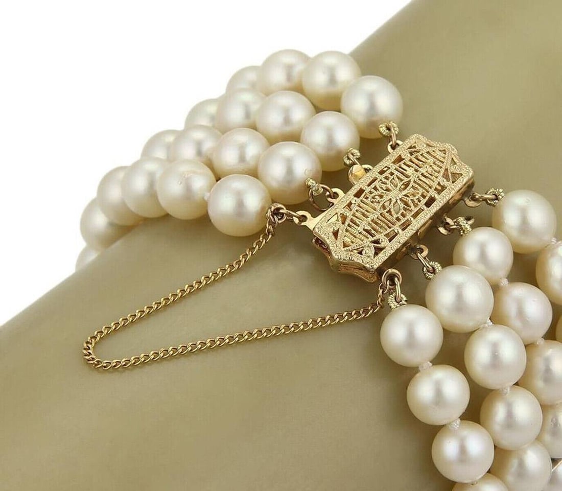 Four Strand 7mm Pearl Bracelet with 14k Yellow Gold Filigree Clasp: Four Strand 7mm Pearl Bracelet with 14k Yellow Gold Filigree Clasp This vintage bracelet features four strands of creamy 7 mm pearls, elegantly set with a rectangular box clasp crafted in 14k yellow g