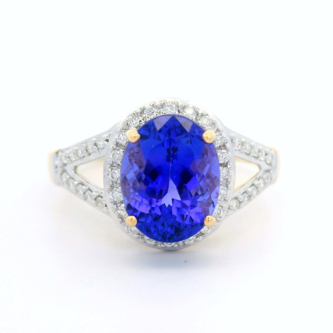 14k Yellow Gold Tanzanite Diamond Halo Cocktail Ring 2.3ctw: 14k Yellow Gold Tanzanite Diamond Halo Cocktail Ring 2.3ctw Elevate your style with this exquisite 14k Yellow Gold Tanzanite Cocktail Ring featuring a stunning diamond halo. The centerpiece is a natur