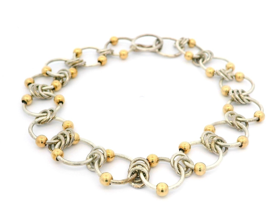 Sterling Silver Bracelet with 10k Yellow Gold Interlocking Links 7.5in: Sterling Silver Bracelet with 10k Yellow Gold Interlocking Links 7.5in This exquisite bracelet features a chain design crafted from sterling silver with beautiful 10k yellow gold accents. The round ri