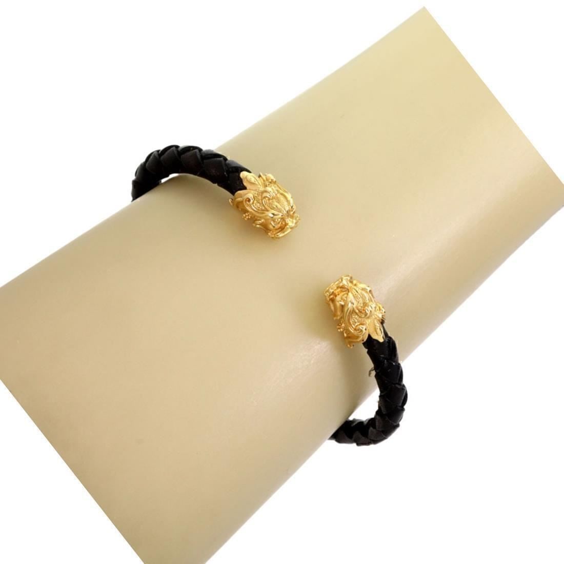 18k Yellow Gold Cuff Bracelet with Woven Leather and Dragon Heads by Carrera y Carrera: 18k Yellow Gold Cuff Bracelet with Woven Leather and Dragon Heads by Carrera y Carrera This cuff bracelet by Carrera y Carrera is crafted from 18k yellow gold and features a woven leather cord. The de