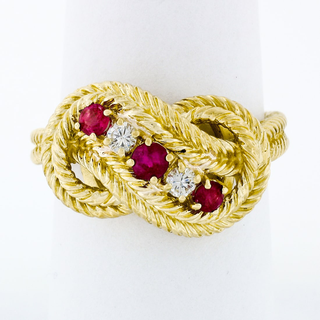 18k Yellow Gold Braided Knot Ring with Ruby and Diamond Accents: 18k Yellow Gold Braided Knot Ring with Ruby and Diamond Accents This exquisite 18k Yellow Gold Braided Loop Knot Band Ring showcases a stunning combination of natural rubies and diamonds. The intricat