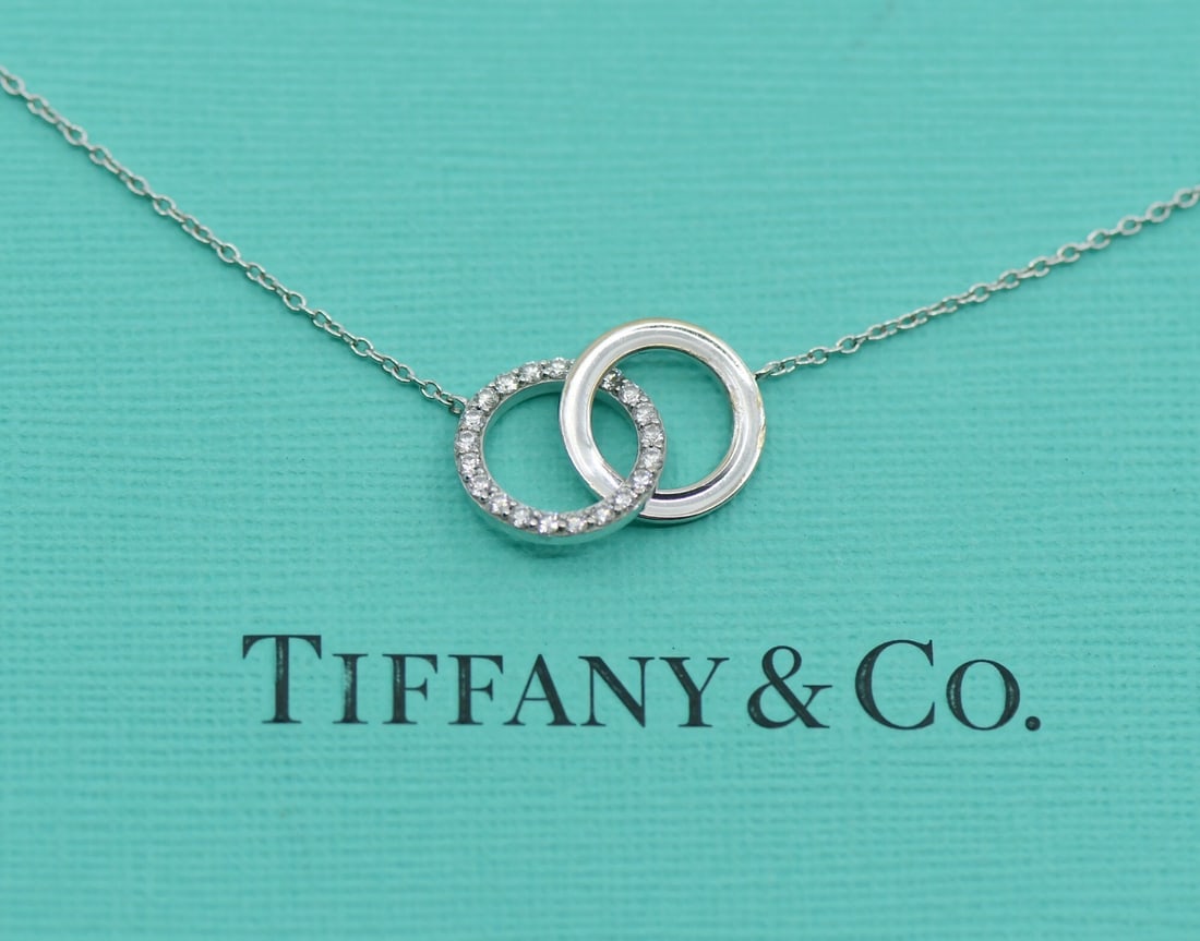 18k White Gold Interlocking Pendant Necklace with Diamonds by Tiffany & Co: 18k White Gold Interlocking Pendant Necklace with Diamonds by Tiffany & Co This Tiffany & Co. necklace features an elegant interlocking pendant design set with diamonds, crafted from 18k white gold. T