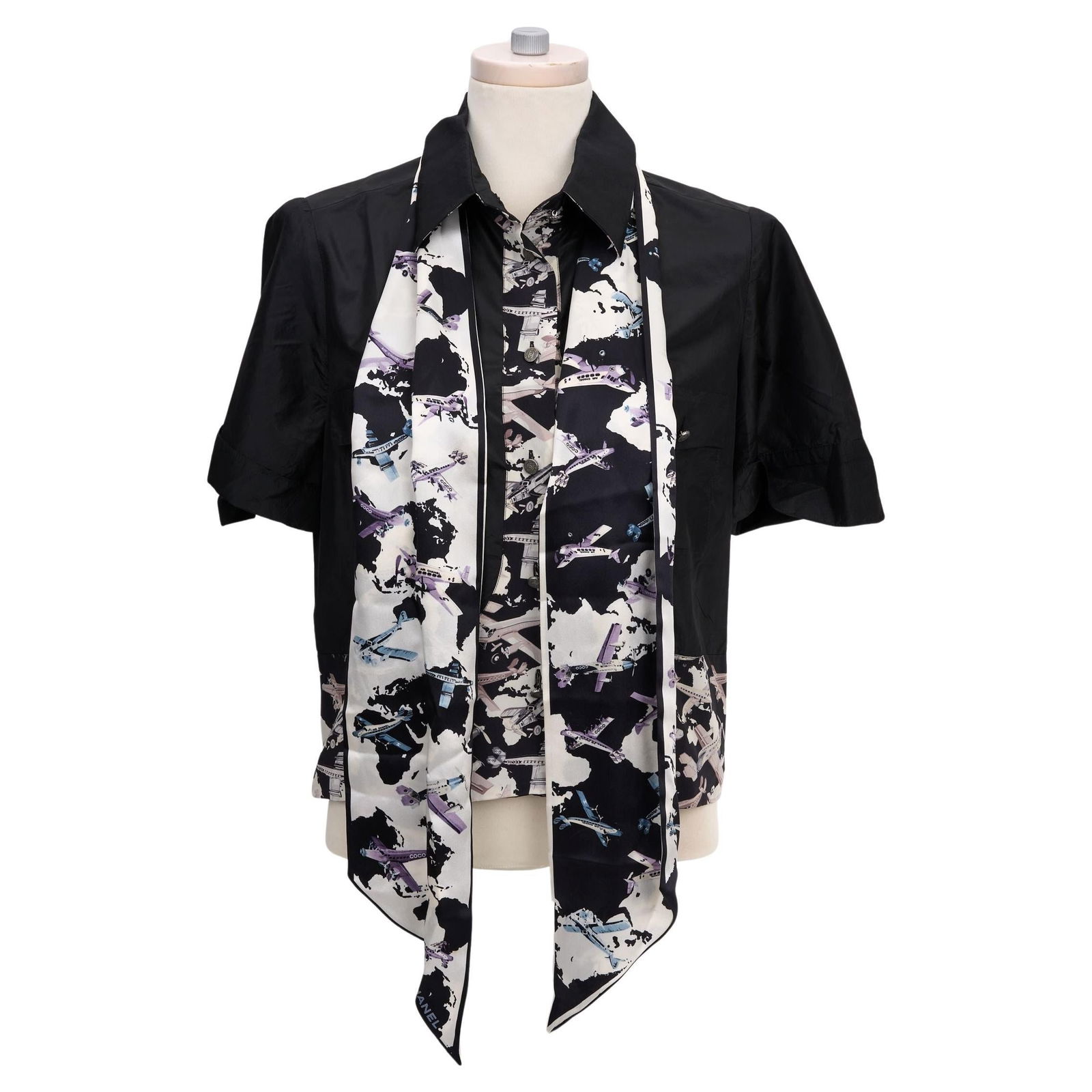 Chanel Black Silk Blouse with Airplane Print and Sash: Chanel Black Silk Blouse with Airplane Print and Sash Elevate your wardrobe with this Chanel Black Silk Button Blouse, crafted from luxurious 100% silk and adorned with iconic CC buttons. The blouse f